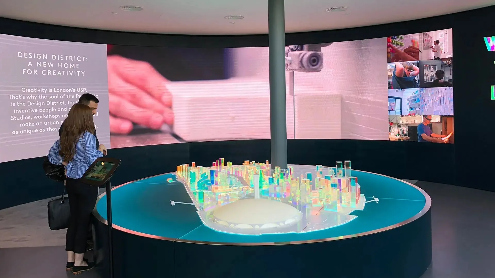 Visitors gathered around an illuminated model of the peninsula beneath a curved projection wall