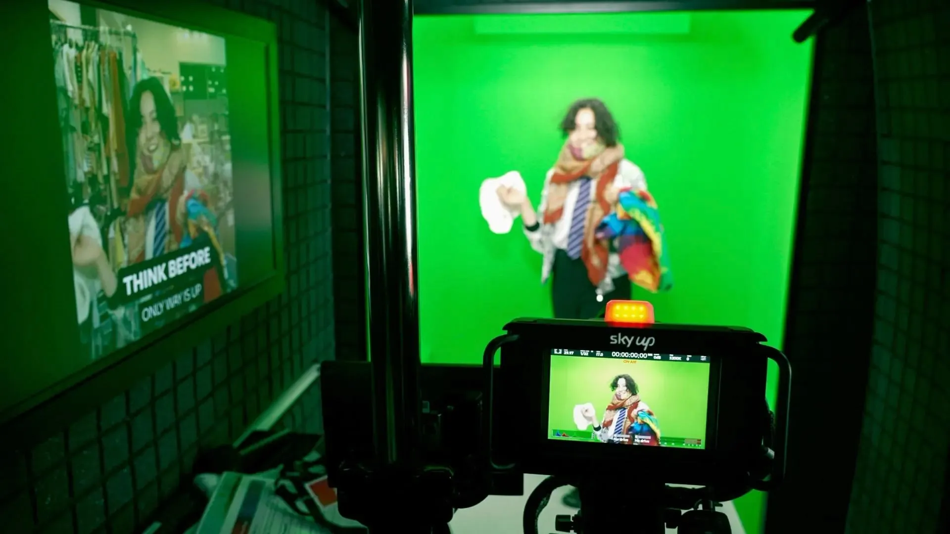 A presenter on the green screen, framed on a camera monitor