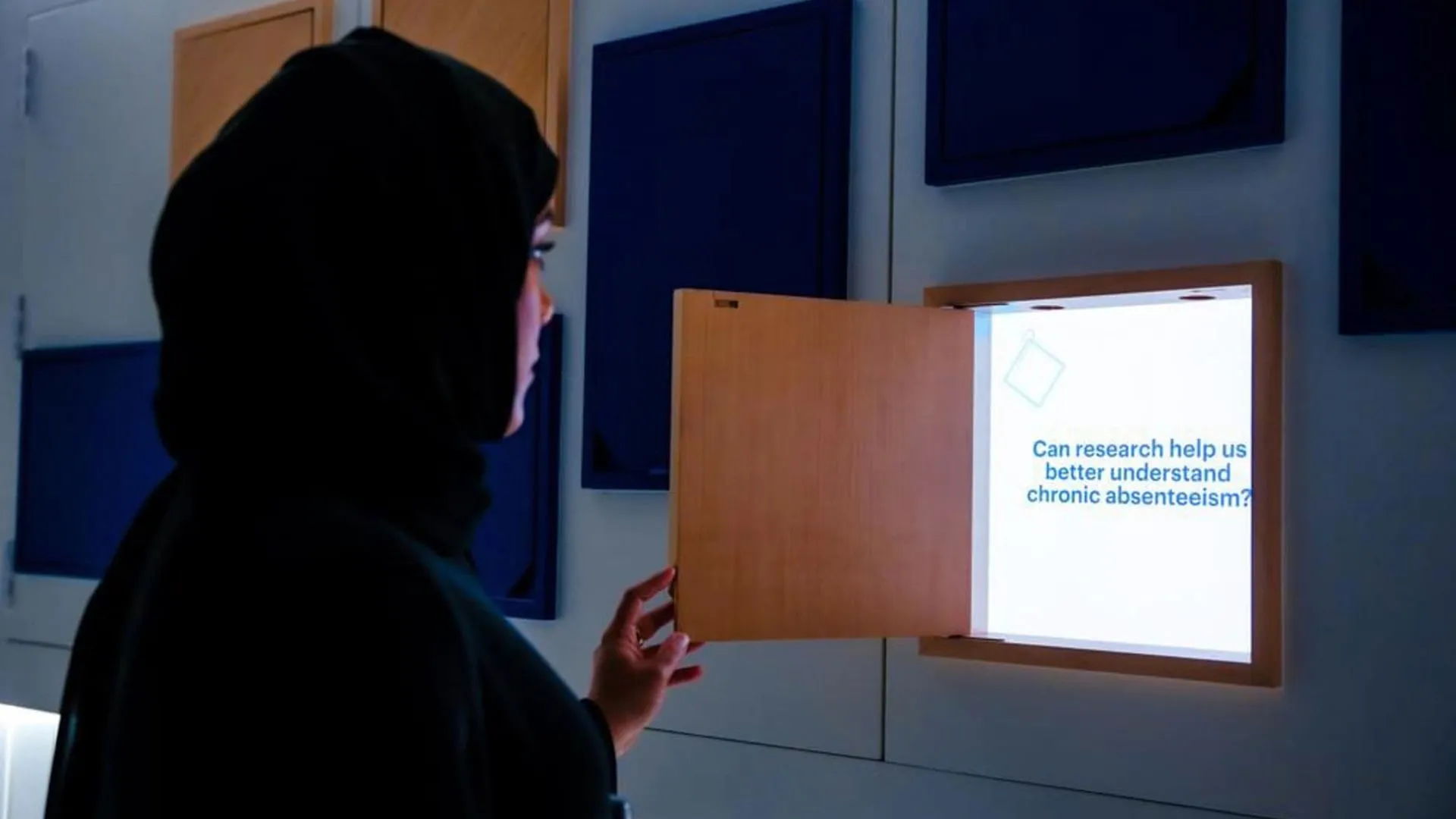 A visitor opening a small door to reveal an interactive screen
