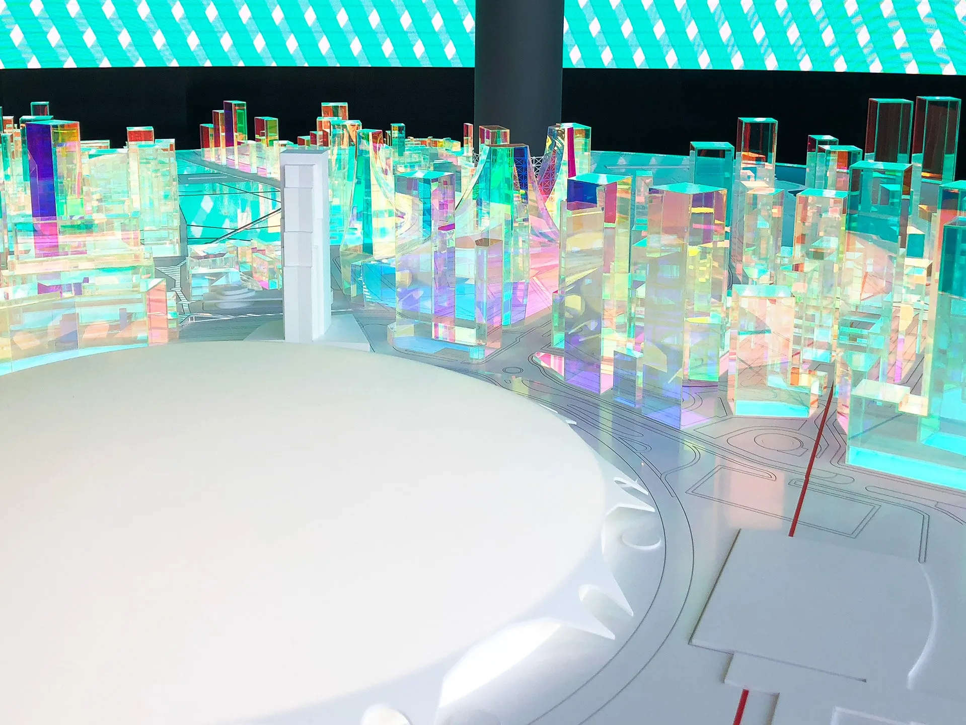 Iridescent model buildings around a white central platform