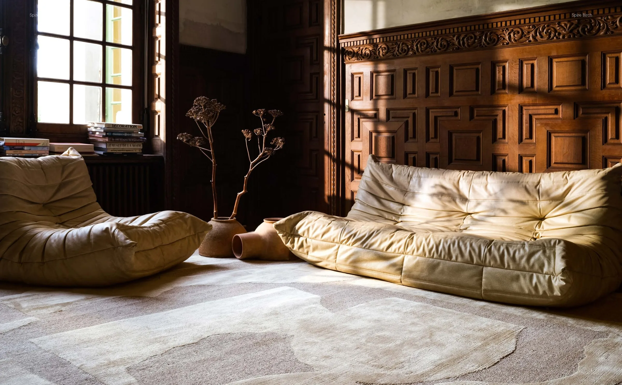 Leather sofas on a large textured rug in a panelled room