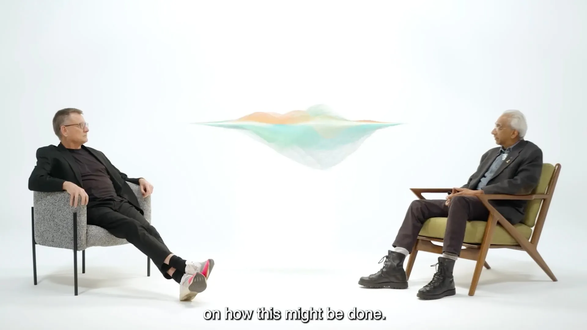 Two speakers in conversation in a white studio, with a floating digital landscape between them